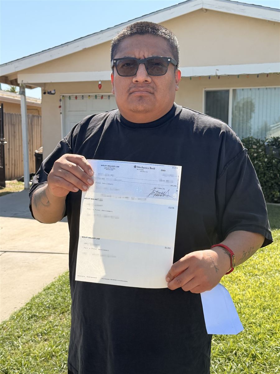 Mario in front of his house holding his case documents
